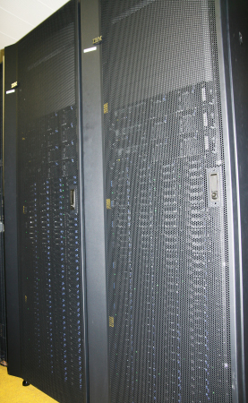 front of two racks containing a few servers and many hard discs